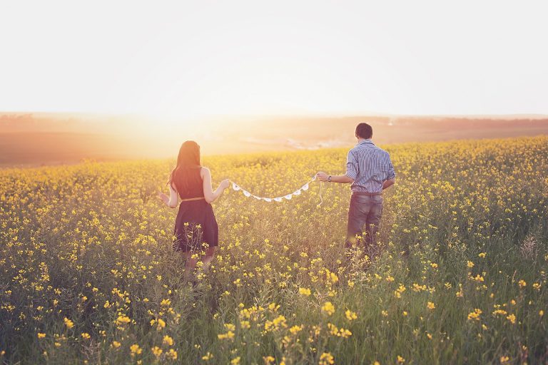 A couple in a country field as the sun is setting